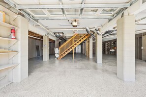 Ambiente spazioso con scala centrale a vista, condotti aperti e un estintore su uno scaffale.