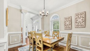 Comedor con mesa de madera, sillas, candelabro y decoración en la pared.
