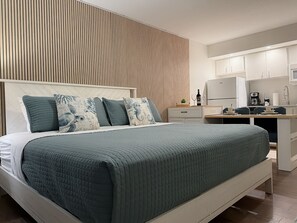 A modern bedroom with a bed, bedside tables, a desk, and a kitchenette. - King Bed, full bath and full kitchen,beach access (Daytona Beach)