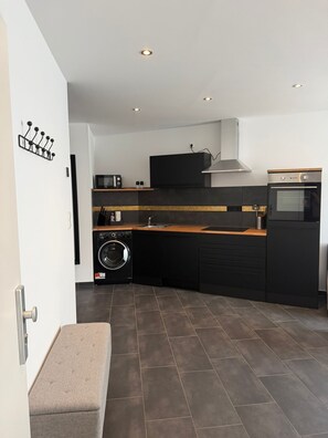A modern kitchen with a washing machine, a microwave, and a built-in oven. - RS Home CB 1 - Stylish apartment for vacation & business (Cottbus)