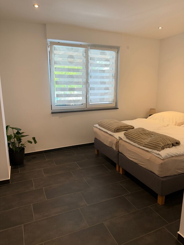 A bedroom with a bed, a potted plant, and a window with blinds. - RS Home CB 1 - Stylish apartment for vacation & business (Cottbus)