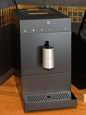 A modern, compact coffee machine with a digital display, a water reservoir, and a power cord. - RS Home CB 1 - Stylish apartment for vacation & business (Cottbus)