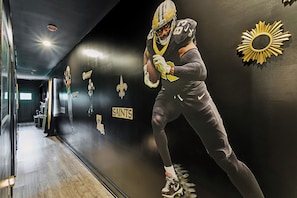 A corridor with a football player, wall decorations, and a sign that reads 'SAINTS'.