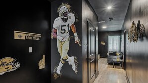 Un corridoio con un murale raffigurante un calciatore, una porta e un tavolino con una lampada.