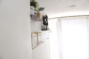 A white wall with a shelf holding decorative items and a framed picture. - 3-bedroom house in Tampa near USF & Bush Gardens - Fenced Yard (Tampa)