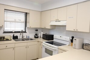 A kitchen with white cabinets, a stove, an oven, a microwave, and a sink. - 3-bedroom house in Tampa near USF & Bush Gardens - Fenced Yard (Tampa)