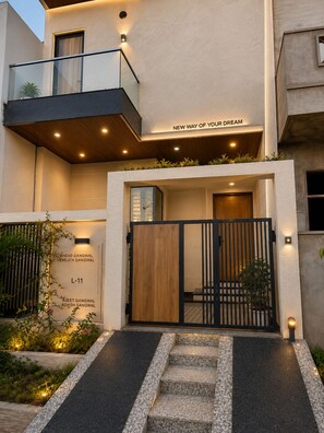 Ein modernes Gebäude mit geschlossenem Eingang, einem Balkon und einem Schild mit der Aufschrift 'NEW WAY OF YOUR DREAM'.