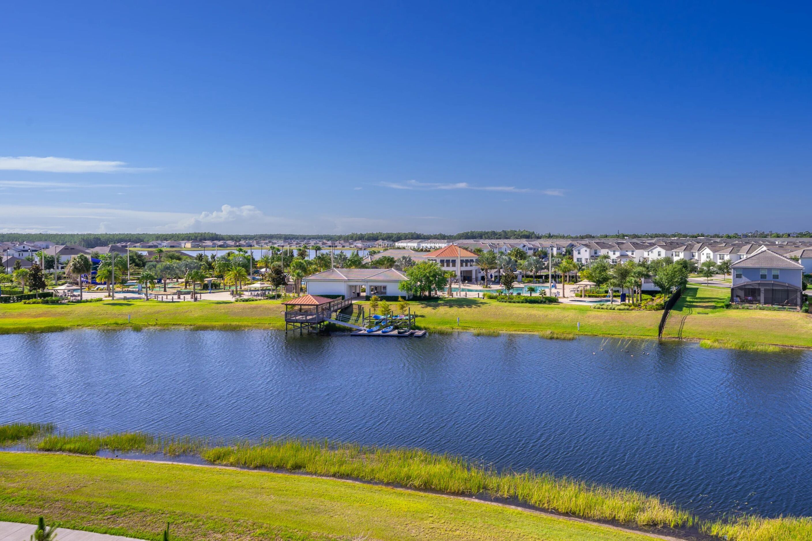 Una zona residencial con casas, un lago y un muelle con barcos.