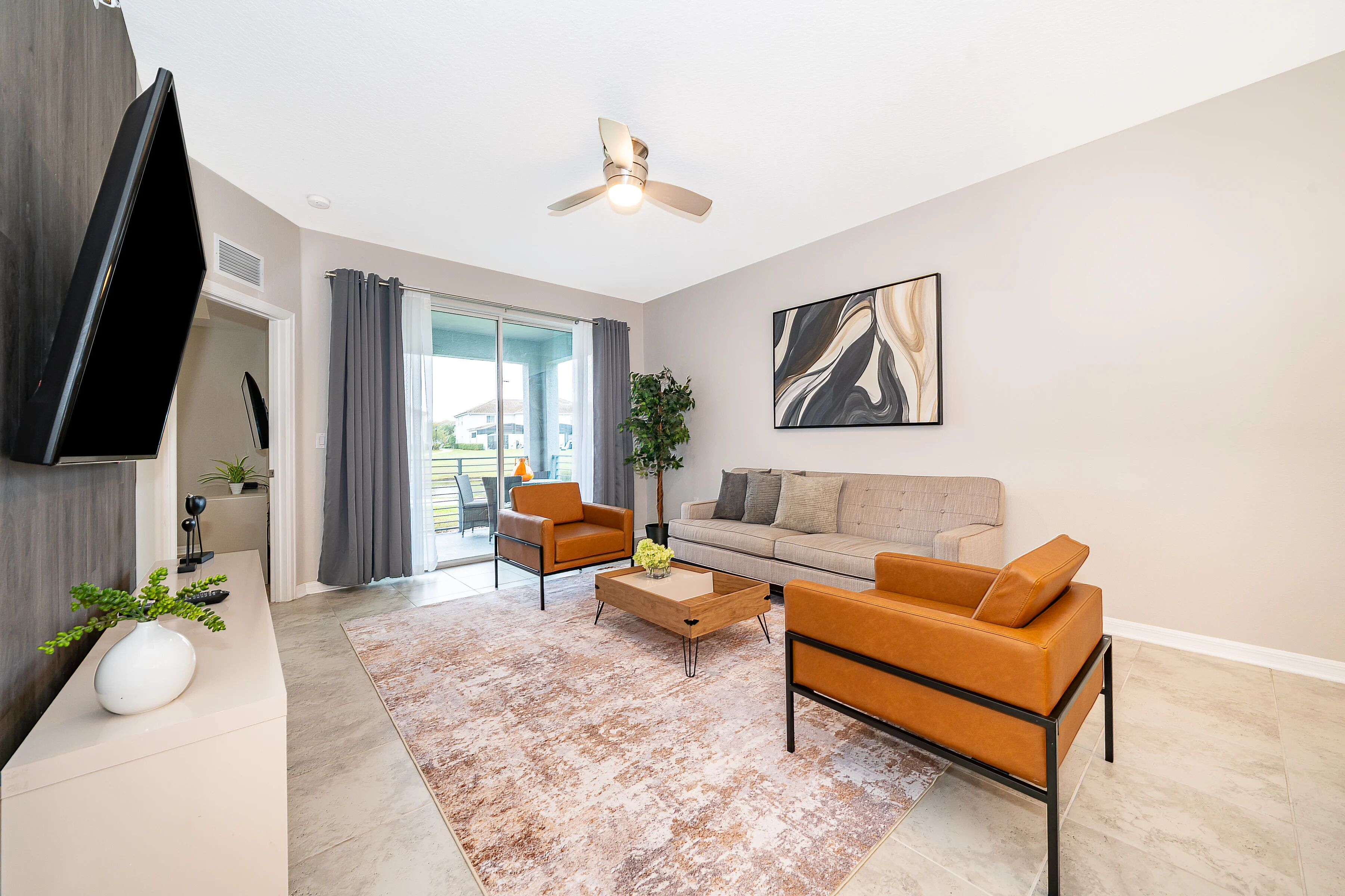 A modern living room with a sofa, two armchairs, a coffee table, and a flat-screen TV.