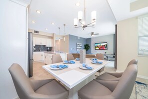 A modern dining area with a white table set for four, beige chairs, and a ceiling fan. - AEA - 3141 Paradox Circle FL (Kissimmee)