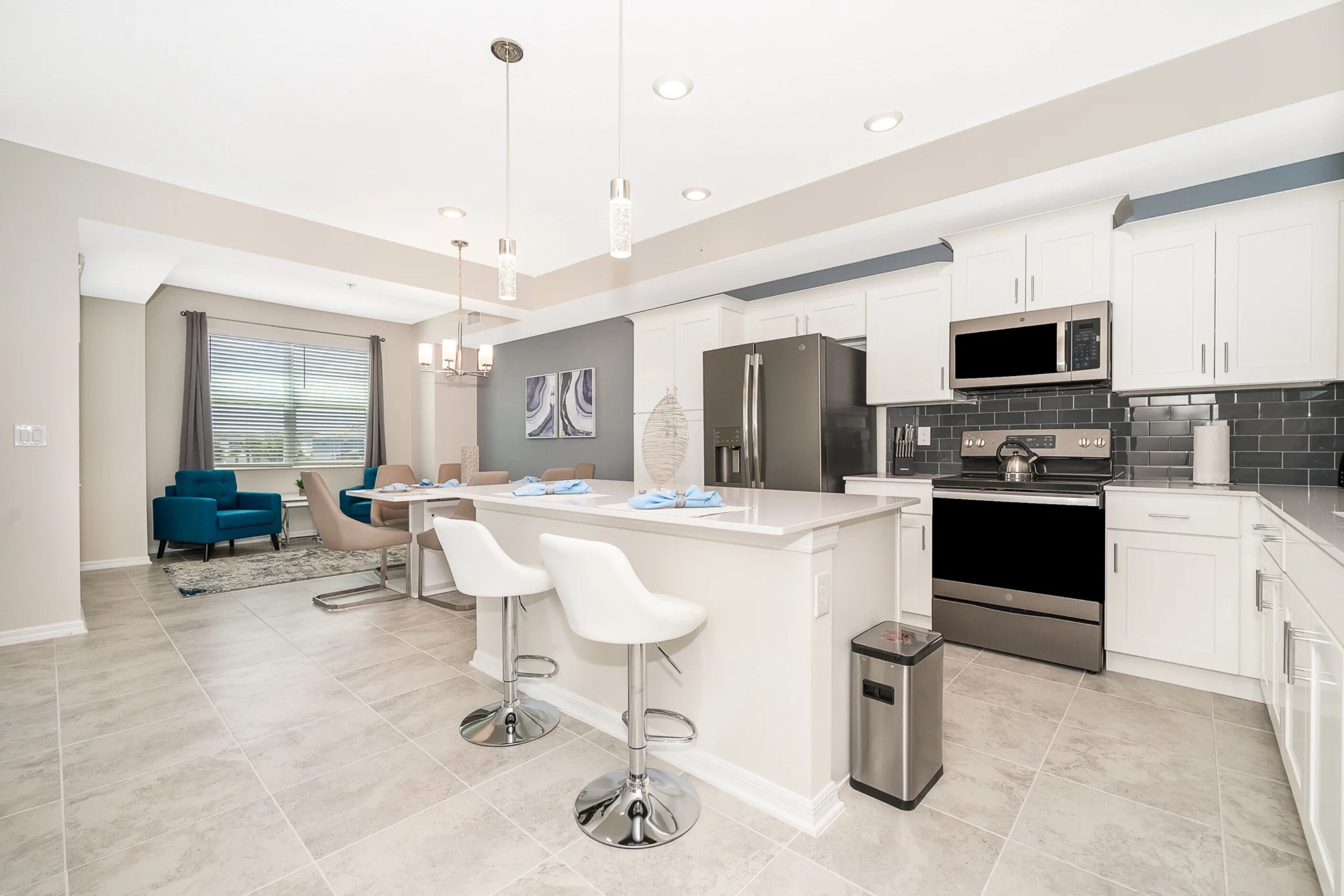 A modern kitchen with white cabinets, stainless steel appliances, and a central island with bar stools.