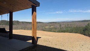 A covered outdoor area with a swing, a wooden post, and a view of a hilly landscape. - Mountain Top Sunsets on 12 secluded acres!  Brand new house finished in 2026 (Mena)