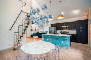A modern kitchen with a central island, black cabinets, and a staircase with a glass railing. - The EaDo Compound: Main house + Guest House (Houston)