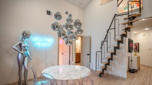A modern interior with a marble table, clear chairs, a metallic disco ball, and a staircase. - The EaDo Compound: Main house + Guest House (Houston)