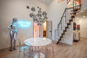 A modern interior with a marble table, clear chairs, a metallic disco ball, and a staircase. - The EaDo Compound: Main house + Guest House (Houston)