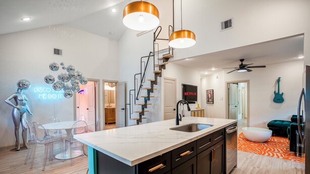 A modern kitchen with a central island, black cabinets, and a white countertop. - The EaDo Compound: Main house + Guest House (Houston)