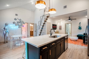 A modern kitchen with a central island, black cabinets, and a white countertop. - The EaDo Compound: Main house + Guest House (Houston)