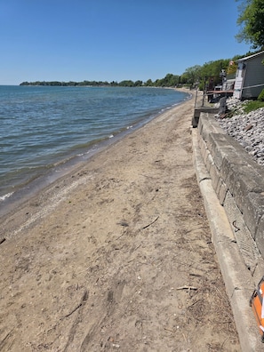 Une plage de sable avec un mur de pierres et un bâtiment sur lequel flotte un drapeau.