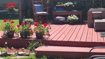 Une terrasse en bois agrémentée de plantes en pot, d’une chaise et d’une table.