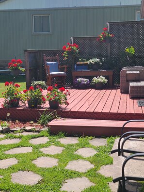 A wooden deck with potted plants, a chair, and a table.