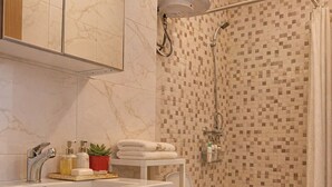 Un baño con tocador de mármol, ducha con pared de mosaicos y un inodoro.