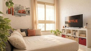 A bedroom with a bed, a TV, a bookshelf, and a window.