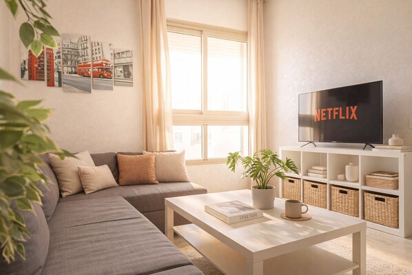 A living room with a sofa, a coffee table, a TV, and a bookshelf.