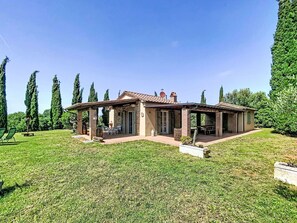 Ein Haus mit Terrasse, Steinmauern und einem Garten.