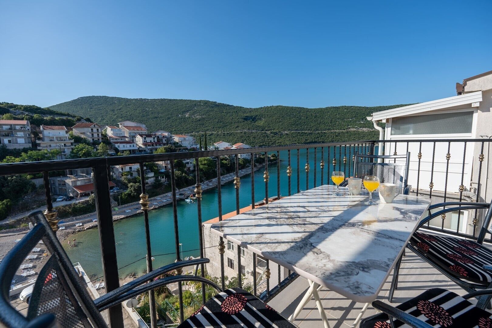A balcony with a view of a river, a town in the background, and a clear sky.