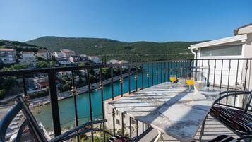 A balcony with a view of a river, a town in the background, and a clear sky.