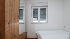 Una camera da letto con un armadio in legno, un letto e una finestra con persiane.