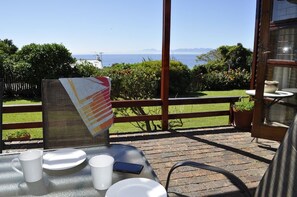 Une terrasse avec une table dressée pour deux personnes, une vue sur la mer et un panneau avec une inscription.