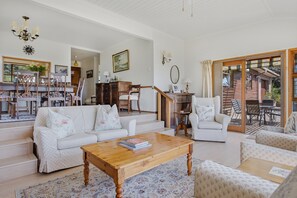 Un salon spacieux comprenant un canapé, des fauteuils, une table basse et un escalier menant à un espace extérieur.