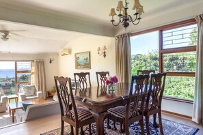 A dining area with a table, chairs, and a view of the outdoors. - Views, Beaches, Barbeques and more at Tom's Cabin: 3 Bedrooms, Sleeps 6 (Cape Town)