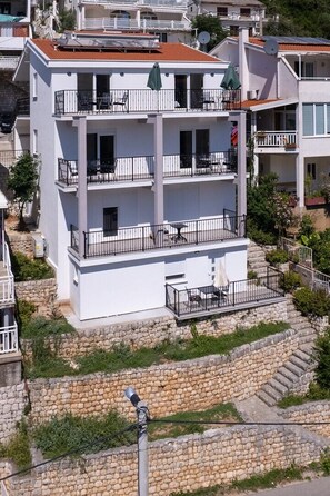 Un immeuble à plusieurs étages doté de balcons, d’escaliers en pierre et de mobilier d’extérieur.