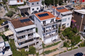 Un immeuble à plusieurs étages, doté de balcons, de panneaux solaires sur le toit et d’un escalier en pierre menant à l’entrée.