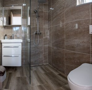 A modern bathroom with a glass shower enclosure, a white sink with a mirror, and a toilet. - Cozy apartment 3 with sea view (Neum)