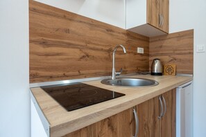 A kitchen with a wooden backsplash, stainless steel sink, and a kettle. - Cozy apartment 3 with sea view (Neum)