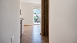 En gang der fører til en balkon med udsigt over bygninger og et bjerg.