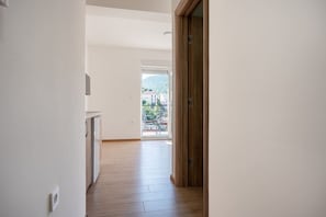 Ein Flur, der zu einem Balkon mit Blick auf Gebäude und ein Bergmassiv führt.