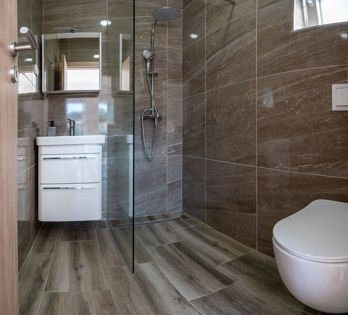 A modern bathroom with a glass shower enclosure, a white sink, and a toilet.