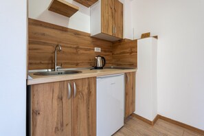 Una cucina compatta con mobili in legno, un lavello in acciaio inossidabile, una macchina da caffè e una lavastoviglie bianca.