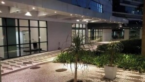 Une cour d’hôtel avec un sol carrelé, des plantes en pot et une façade de bâtiment moderne.