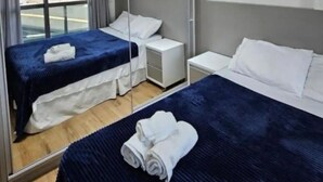 Une chambre d’hôtel avec deux lits, un grand miroir, une fenêtre avec des rideaux et une vue sur la ville.