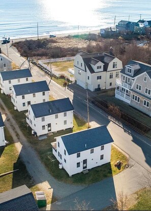 Et boligområde med flere hvide huse, en vej og et vandareal i baggrunden.