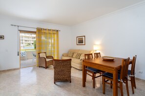 Ein Wohnzimmer mit einer Couch, Esstisch, Stühlen und einem Balkon mit Blick.