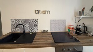 Een keuken met een zwart spoelgedeelte, een kookplaat en een spatwand met patroontegels.