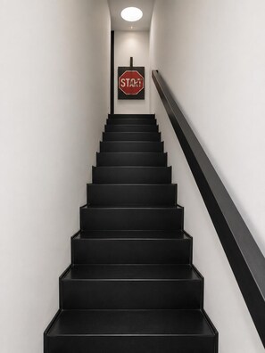 Eine Treppe mit schwarzen Stufen und einem schwarzen Geländer, die zu einem Stoppschild führt.