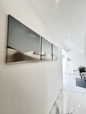 A modern interior with a marble floor, a sofa, and a wall-mounted artwork depicting a desert landscape. - 06 AN - Stay Monte Paradise (Ayia Napa)