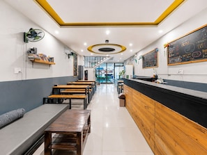 A cafe interior with wooden benches, a counter, and a chalkboard menu. - Two Horses Hostel (Hoi An)